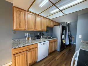 Kitchen featuring dishwasher, sink, stainless steel fridge, dark hardwood / wood-style flooring, and range