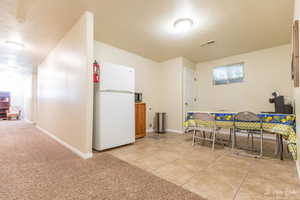 Kitchen with light tile patterned flooring and white refrigerator