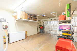 Garage featuring a garage door opener, fridge, white fridge, and water heater