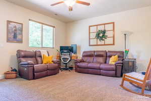 Carpeted living room featuring ceiling fan