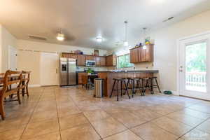 Kitchen featuring light tile patterned floors, a kitchen breakfast bar, kitchen peninsula, pendant lighting, and stainless steel appliances