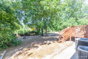 View of yard with central AC unit and a deck