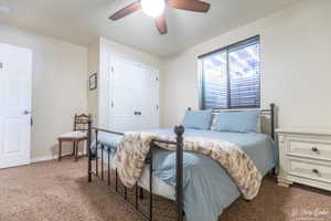 Carpeted bedroom featuring ceiling fan and a closet