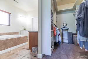 Bathroom featuring vanity, tile patterned flooring, and a relaxing tiled tub