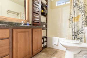 Full bathroom with vanity, toilet, tile patterned flooring, and shower / tub combo