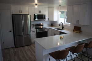 Kitchen with stainless steel appliances, white cabinetry, sink, and kitchen peninsula