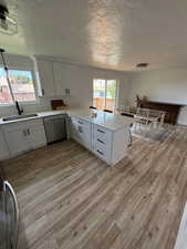 Kitchen featuring sink, white cabinets, kitchen peninsula, and dishwasher