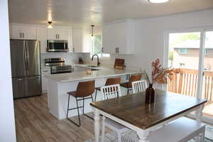 Kitchen with sink, white cabinetry, a healthy amount of sunlight, pendant lighting, and stainless steel appliances