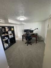 Office space featuring a textured ceiling and carpet