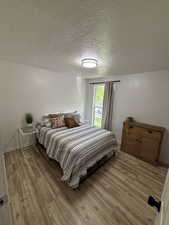 Bedroom with a textured ceiling and light wood-type flooring