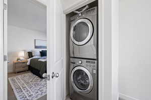 Laundry area featuring stacked washer and clothes dryer and carpet