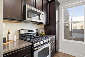 Kitchen featuring dark brown cabinetry, dark hardwood / wood-style flooring, and appliances with stainless steel finishes