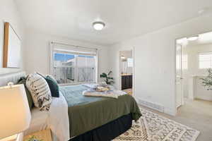 Bedroom with multiple windows, ensuite bath, and light carpet