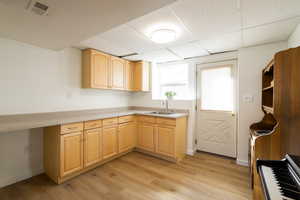 Kitchen featuring light brown cabinetry, sink, outside entry,  and light wood LVP flooring