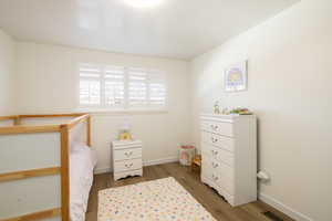 Bedroom with dark wood-type flooring and shutters