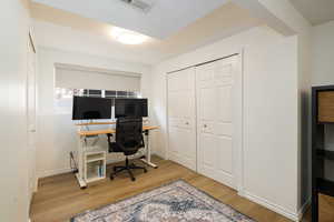 Office in the bedroom with wood-type flooring