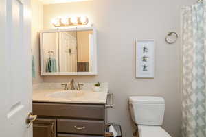 Bathroom featuring vanity toilet, and shower/bath combo with shower curtain