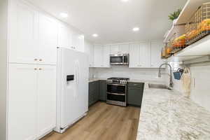 Kitchen featuring white cabinetry, sink, light hardwood / wood-style floors, and appliances with stainless steel finishes