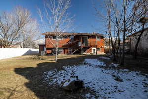 Back of home, featuring large, fenced yard with mature trees, a wooden deck and a shed.