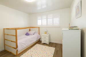 Bedroom featuring hardwood / wood-style floors, and shutters