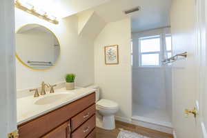 Bathroom featuring vanity, hardwood / wood-style floors, toilet, and walk in shower