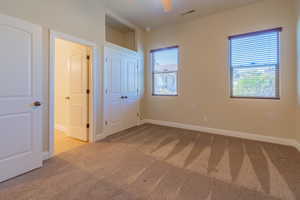 Unfurnished bedroom with light colored carpet and ceiling fan