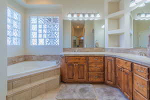 Bathroom with built in features, tasteful backsplash, vanity, a relaxing tiled tub, and tile patterned floors