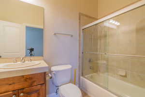 Full bathroom featuring vanity, shower / bath combination with glass door, and toilet