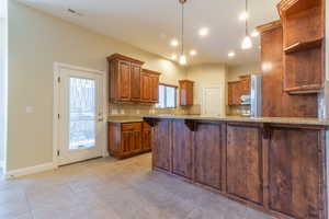 Kitchen featuring tasteful backsplash, a breakfast bar area, light tile patterned floors, and decorative light fixtures