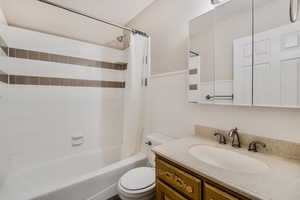 Full bathroom with vanity, shower / bath combination with curtain, and toilet