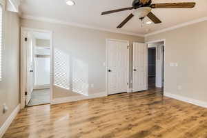 Unfurnished bedroom featuring ensuite bath, ceiling fan, ornamental molding, and light wood-type flooring