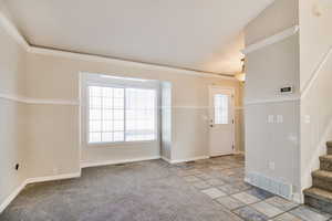 Foyer featuring light carpet, a wealth of natural light, and ornamental molding