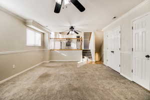 Unfurnished living room featuring carpet flooring, ceiling fan, and crown molding