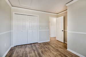 Unfurnished bedroom with hardwood / wood-style flooring, a closet, and ornamental molding