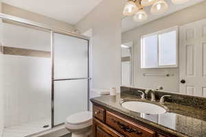 Bathroom featuring an enclosed shower, vanity, and toilet