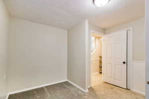 Unfurnished room with light colored carpet and a textured ceiling