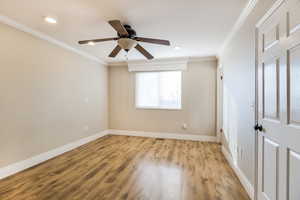 Empty room with ceiling fan, light wood-type flooring, and ornamental molding