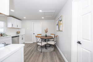 Kitchen with white cabinetry, tasteful backsplash, light hardwood / wood-style floors, and dishwasher