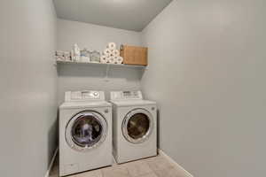 Washroom featuring light tile patterned flooring, separate washer and dryer, and a textured ceiling