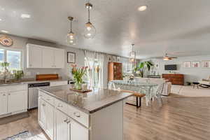 Kitchen with a kitchen island, white cabinetry, sink, hanging light fixtures, and stainless steel dishwasher