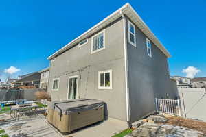 Rear view of house with a trampoline, a hot tub, and a patio