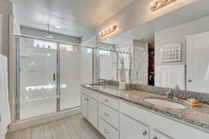 Bathroom featuring vanity, a shower with shower door, and a textured ceiling