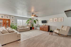 Living room with ceiling fan, carpet, and a textured ceiling