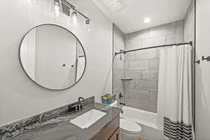 Full bathroom with vanity, shower / bath combination with curtain, and toilet