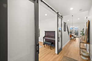 Corridor featuring an inviting chandelier, a barn door, and light wood-type flooring