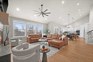 Living room with a premium fireplace, high vaulted ceiling, a wealth of natural light, and light wood-type flooring