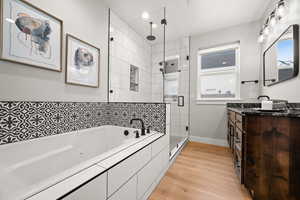 Bathroom featuring wood-type flooring, separate shower and tub, and vanity