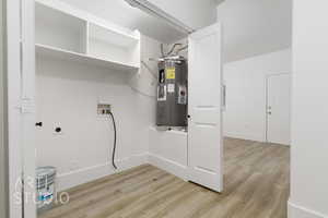 Laundry area with electric dryer hookup, electric water heater, washer hookup, and light wood-type flooring