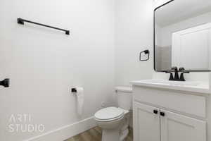 Bathroom with hardwood / wood-style flooring, vanity, and toilet