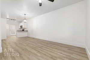 Unfurnished living room with ceiling fan, rail lighting, and light hardwood / wood-style flooring